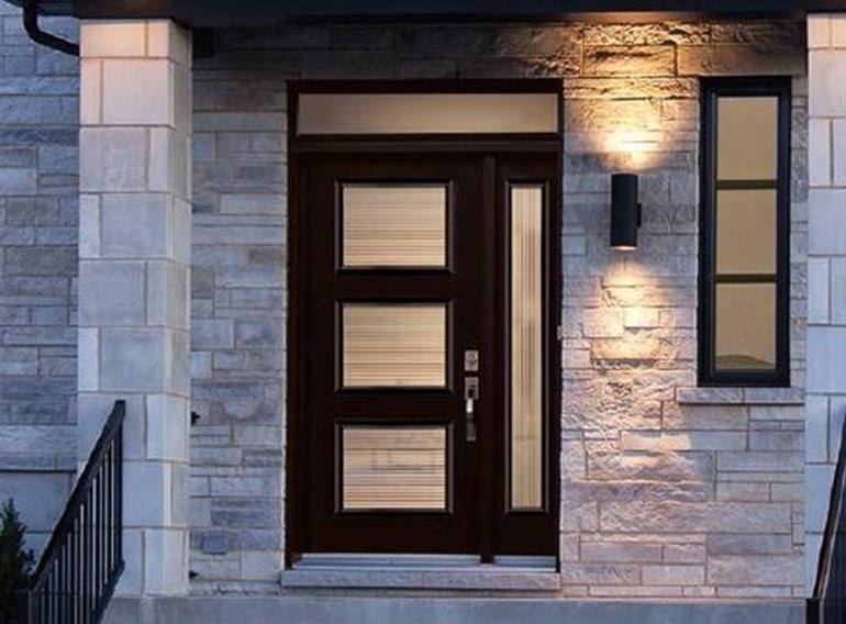 Modern stone entrance with dark door and sidelite